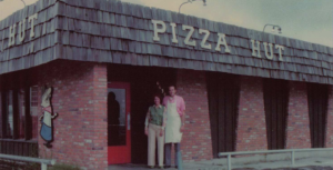 two people stand in front of a Pizza Hut