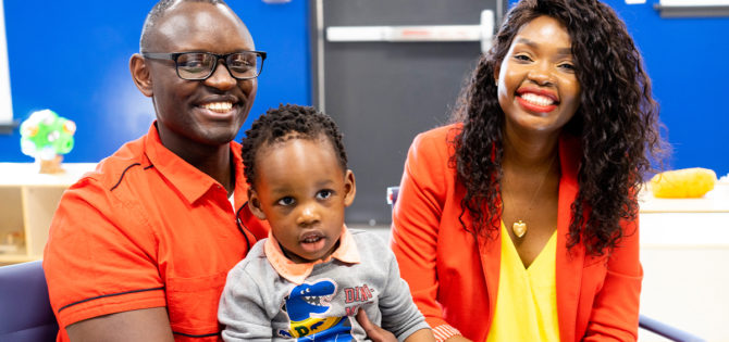 Black couple, smiling, with toddler son on father's lap.