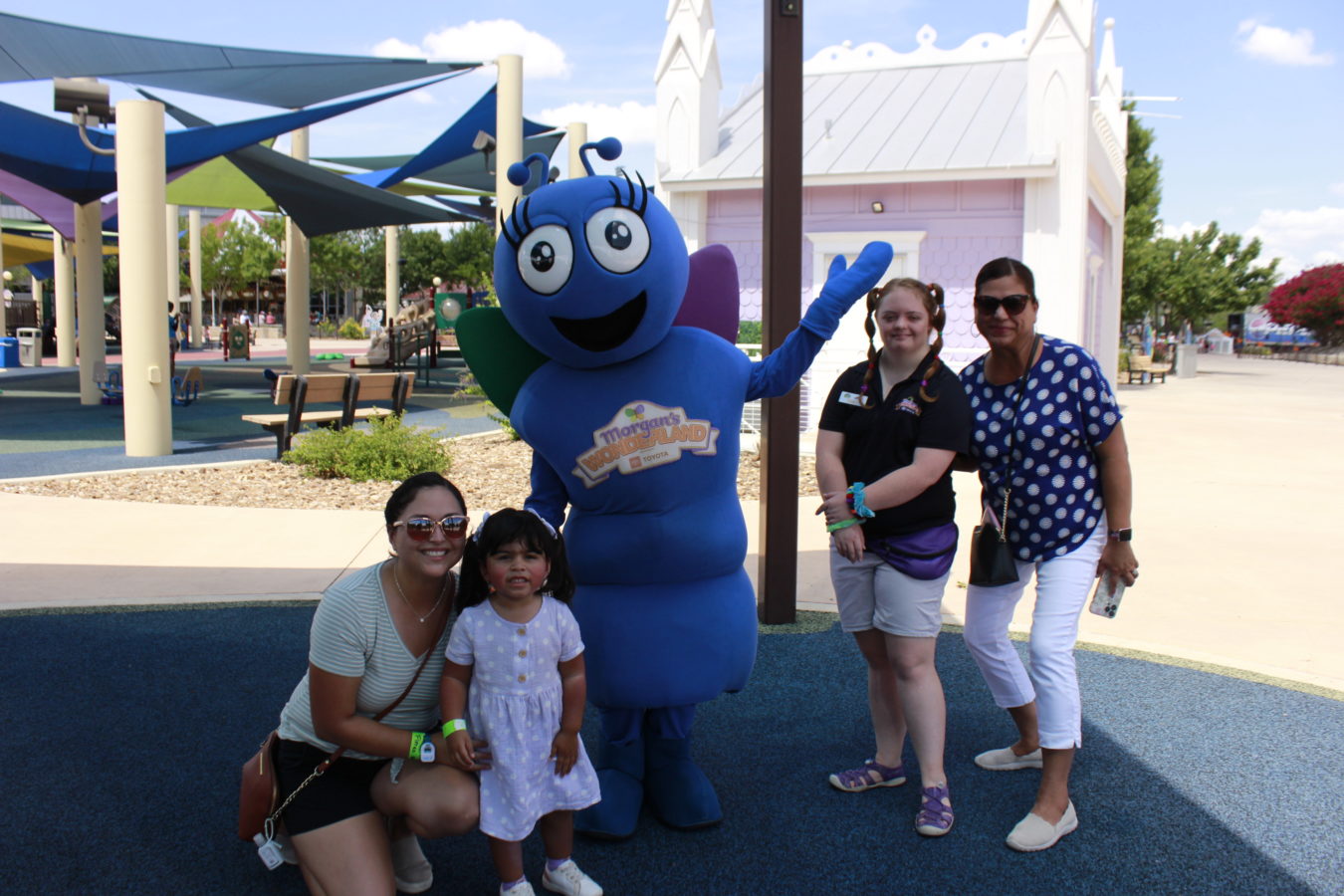 a family poses next to Joy, the Morgan's Wonderland mascot, at United Way's Family Celebration Day