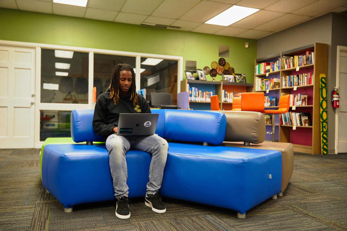 Kiara sits on a couch using a laptop