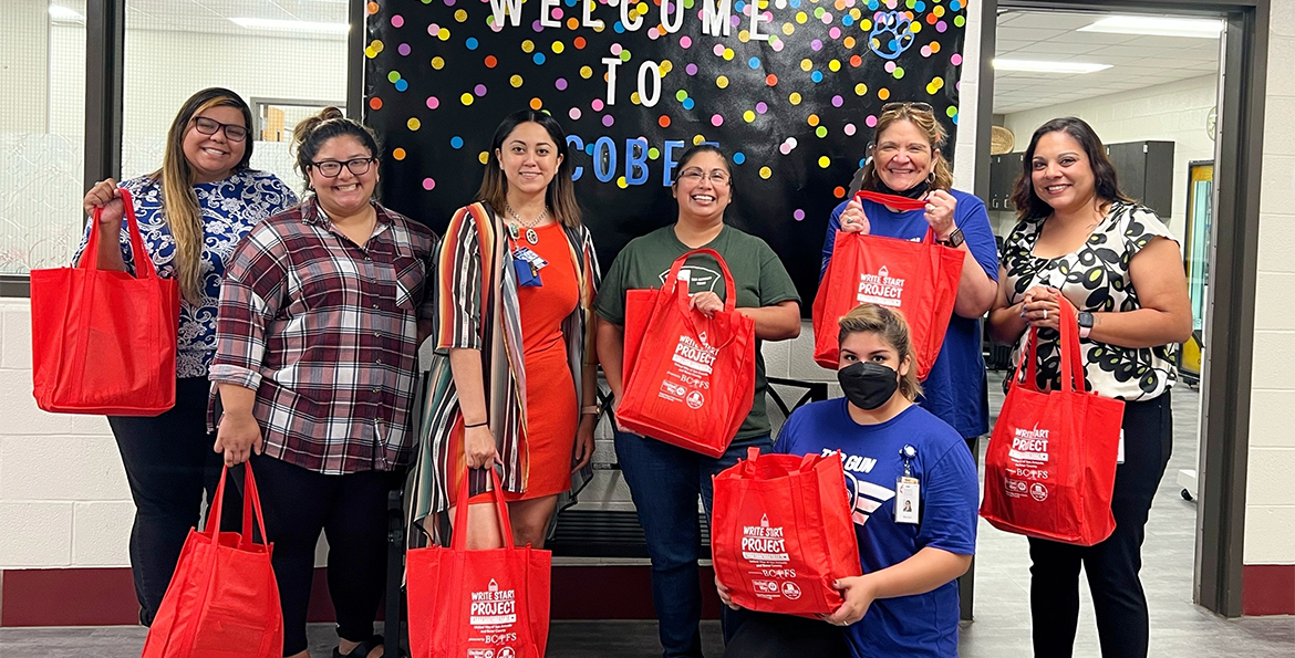 teachers pose with school supply bags